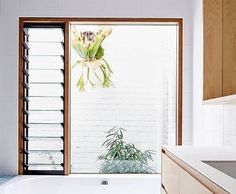 a white bath tub sitting inside of a bathroom next to a wooden cabinet and window