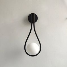 a black and white light hanging on the wall next to a plant in a vase