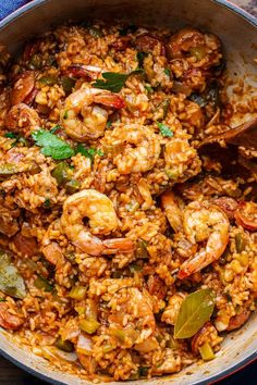 a pot filled with rice and shrimp on top of a wooden table