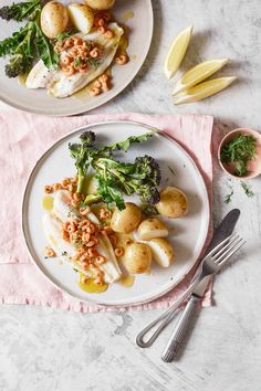 two plates filled with food on top of a pink napkin next to silver utensils