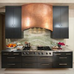 a stove top oven sitting inside of a kitchen next to black cupboards and drawers