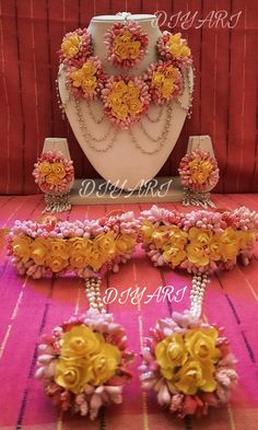 three pieces of jewelry sitting on top of a pink and yellow cloth covered tablecloth