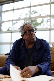 an older man sitting at a table with papers in front of him and looking off to the side