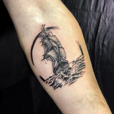 a man's arm with a ship tattoo on it