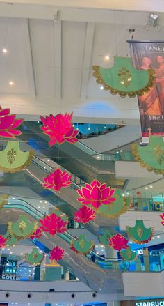 there are many paper flowers hanging from the ceiling in this mall lobby, and it looks like they're floating