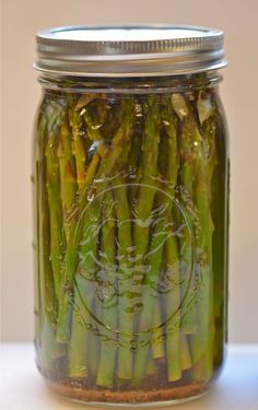 a jar filled with asparagus sitting on top of a table