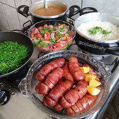 there are many different types of food on the stove top, including sausages and rice