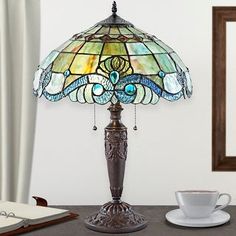 a table lamp sitting on top of a desk next to a cup and saucer