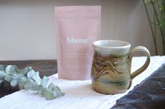 a coffee mug sitting on top of a white towel next to a bag of glume