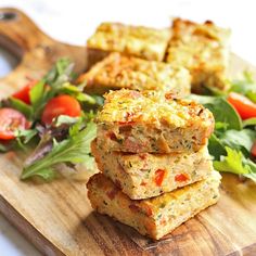 some food is stacked on top of each other with lettuce and tomatoes in the background