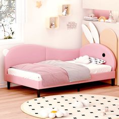 a pink bed with bunny ears on the headboard