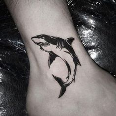 a black and white photo of a shark tattoo on the foot