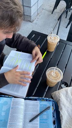 a person sitting at a table with an open book and coffee in front of them