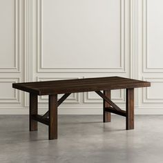 a wooden table sitting on top of a cement floor next to a white paneled wall