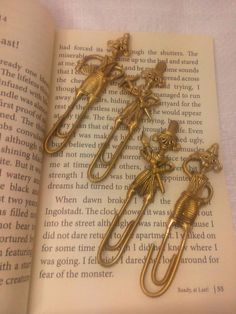 three gold - plated metal bookmarks in the shape of mice on an open book