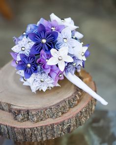 a purple and white bouquet sitting on top of a tree stump