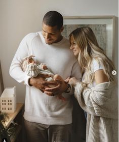 a man and woman holding a baby in their hands