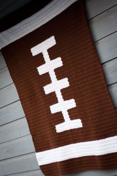 a brown and white crocheted blanket with the word football written in white on it