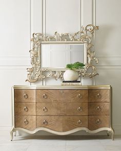 a dresser with a mirror on top of it next to a vase and potted plant