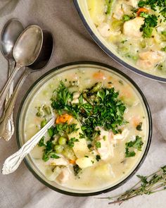 two bowls of chicken and vegetable soup with spoons