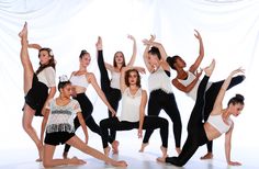 a group of dancers pose in front of a white backdrop with their arms up and legs spread out