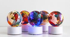 four colorful marbles sitting on top of white bases