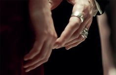 the bride and groom hold hands as they prepare to put their wedding rings on each other