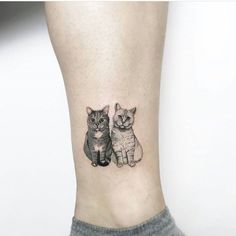 two cats tattoo on the side of a woman's right leg, with one cat looking at the camera