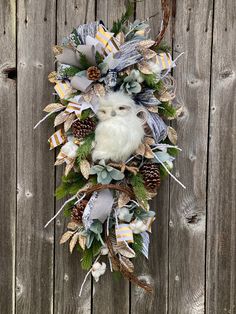 a wreath hanging on the side of a wooden fence with an owl and pine cones