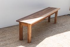 a wooden bench sitting on top of a carpeted floor next to a white wall