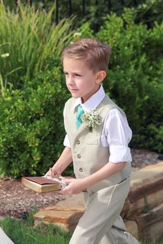 a young boy in a suit and tie holding a book