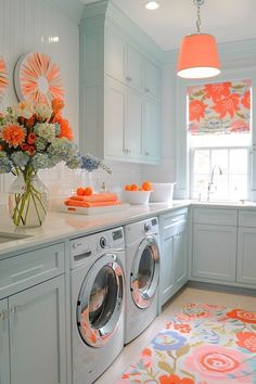 a washer and dryer sitting in a kitchen next to a window with orange flowers