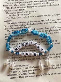 a bracelet with words written in white and blue beads on top of an open book