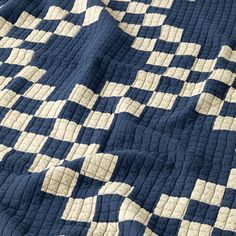 a blue and white checkered quilt on top of a bed