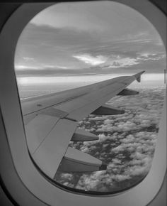 an airplane wing is seen through the window as it flies in the sky above clouds