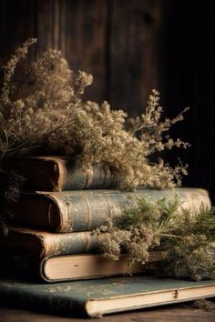 an old stack of books sitting on top of a wooden table next to some plants