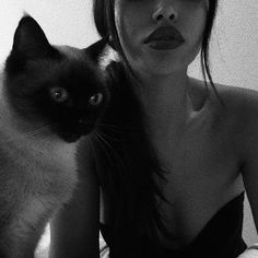 a woman is holding a cat and posing for the camera in black and white photo