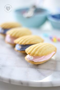 four cookies with pink and blue icing are on a white plate