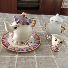 two teapots and saucers sitting on top of a table