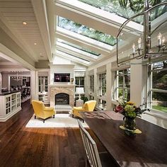 a large open concept kitchen and dining room with skylights on the ceiling, along with hardwood flooring