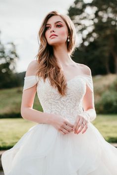 a woman in a wedding dress posing for the camera with her hands on her hips