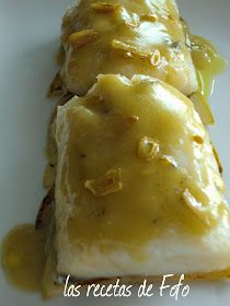 two pieces of fish covered in gravy on top of a white plate with sauce