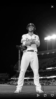 a black and white photo of a baseball player standing on the field with his bat