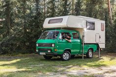 a man sitting in the back of a green truck with a camper attached to it