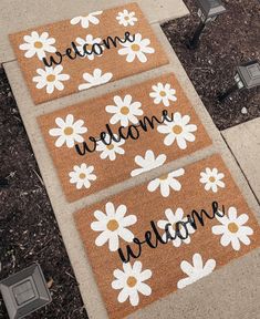 three welcome mats with daisies on them