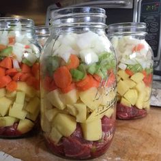 four mason jars filled with different types of food on top of a wooden countertop