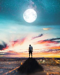 a man standing on top of a hill looking at the sky with a full moon in the background