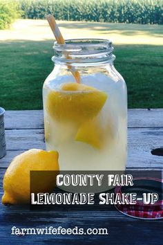 a mason jar filled with lemonade next to some sliced lemons on a picnic table