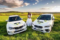 the bride and groom are standing next to two cars in a field with green grass