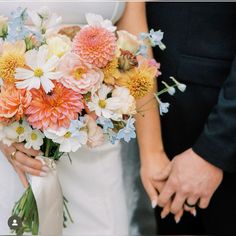 the bride and groom are holding hands with each other while they hold their bouquets